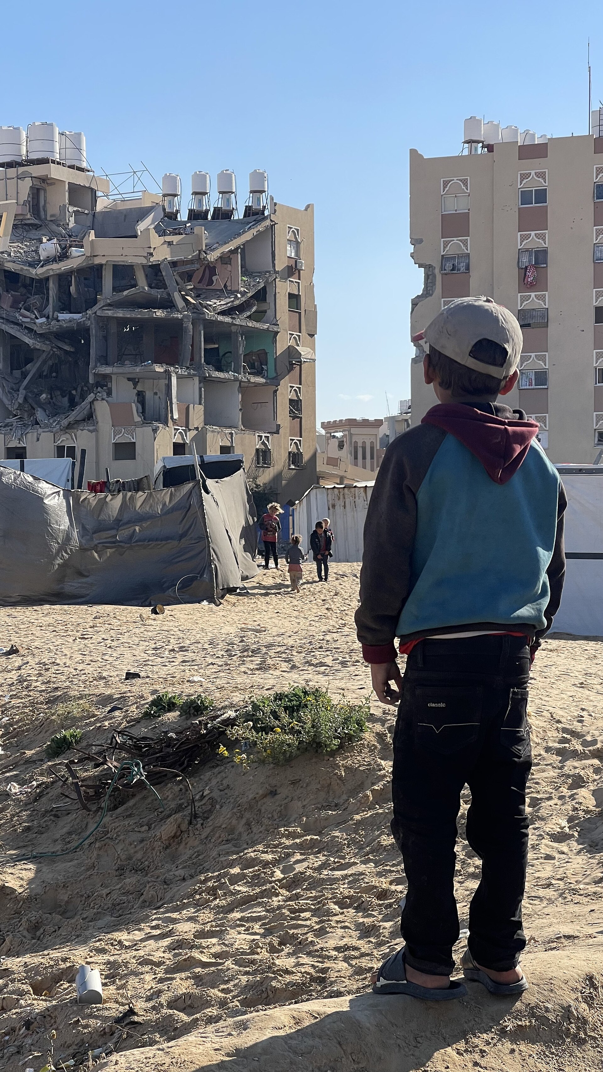 A child in Gaza looks at buildings destroyed in the war